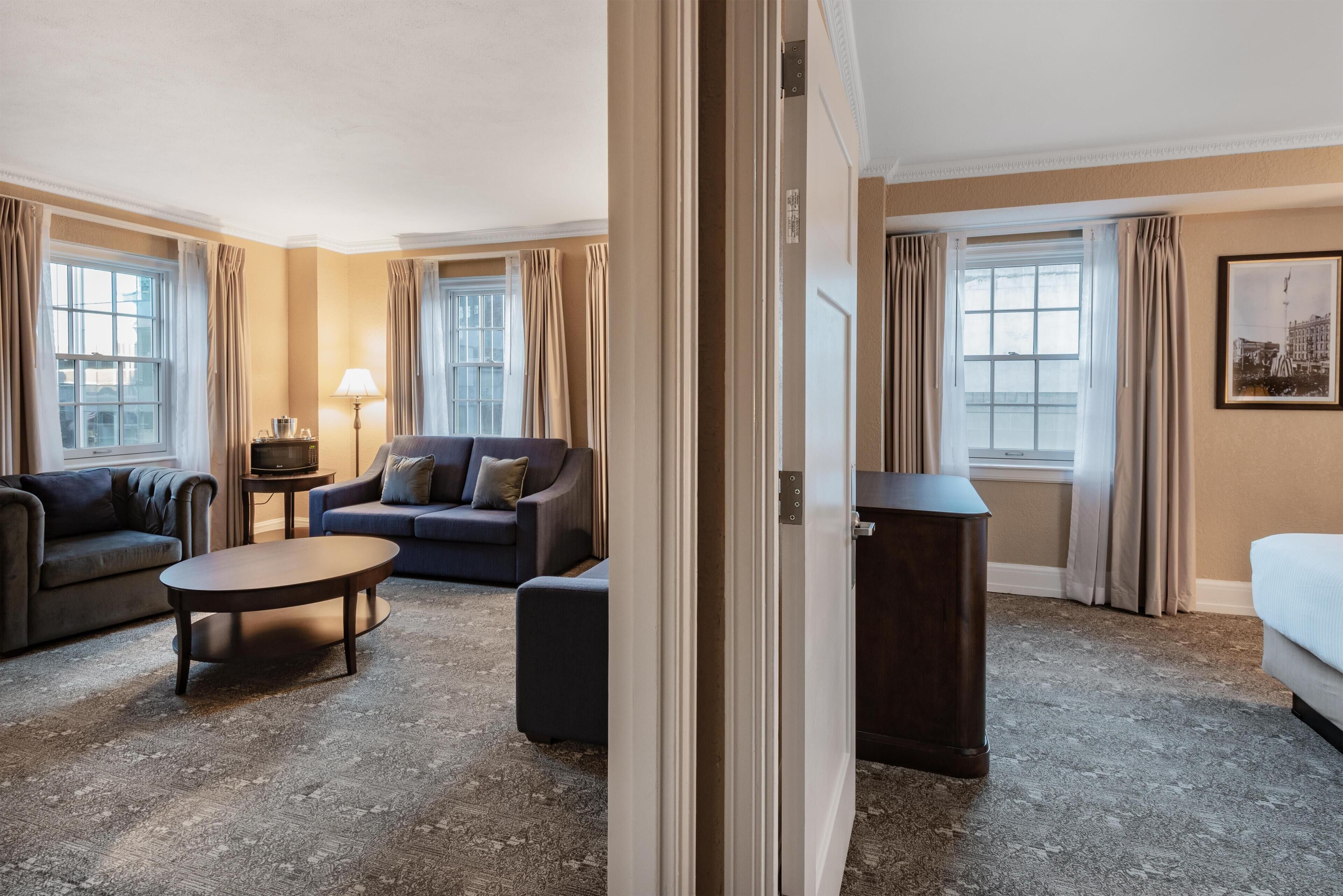 Una habitación de hotel con sofá, mesa de centro, televisión y cama.