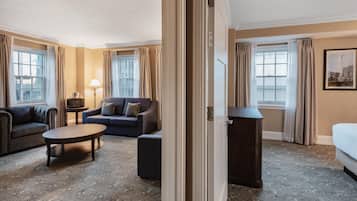 Una habitación de hotel con sofá, mesa de centro, televisión y cama.