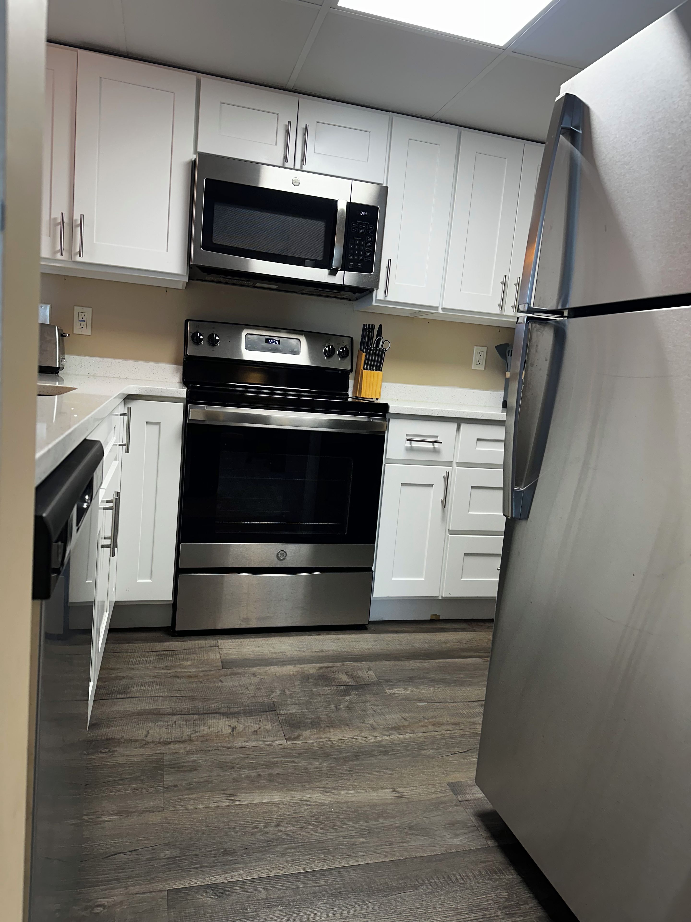 A kitchen with white cabinets, a stainless steel refrigerator, a microwave, and a double oven.