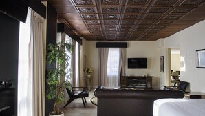 Habitación de hotel con una cama grande, un sofá, un televisor, un escritorio y una planta en maceta.