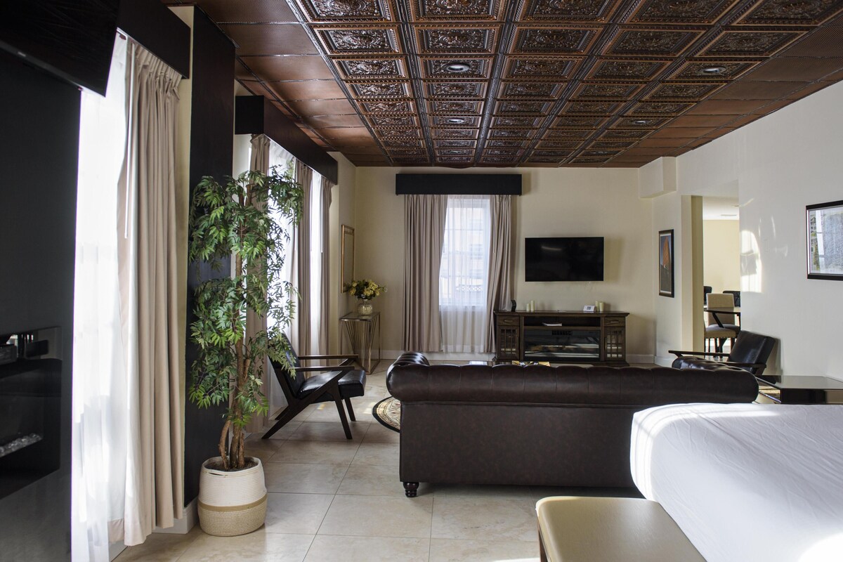 Une chambre d’hôtel avec un grand lit, un canapé, une télévision, un bureau et une plante en pot.