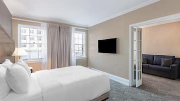 A hotel room with a bed, a TV, a sofa, and a view of the city.