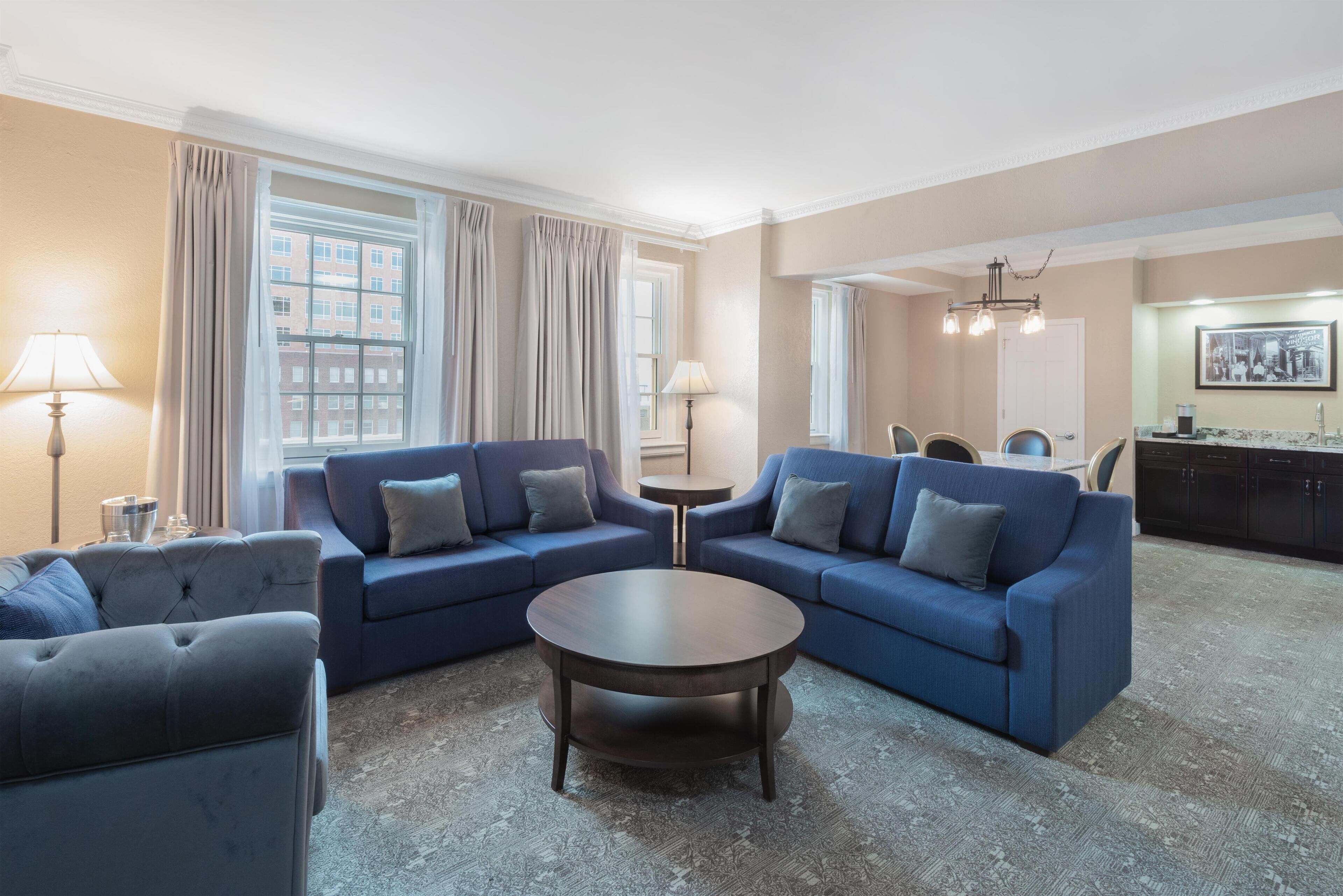 A living room with two sofas, a coffee table, and a dining area with a chandelier.