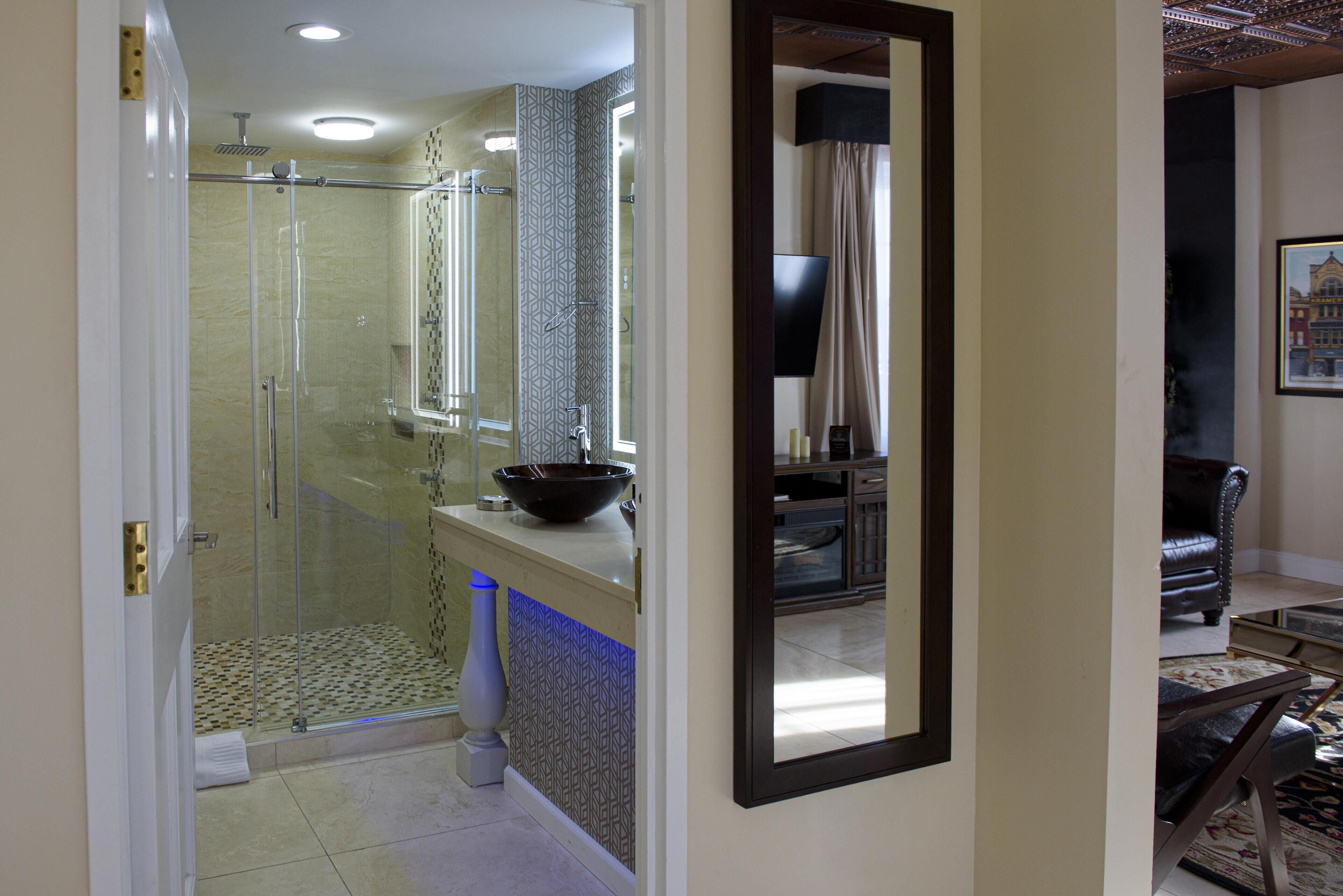 A bathroom with a glass shower enclosure, a sink with a large bowl, and a mirror reflecting the room.