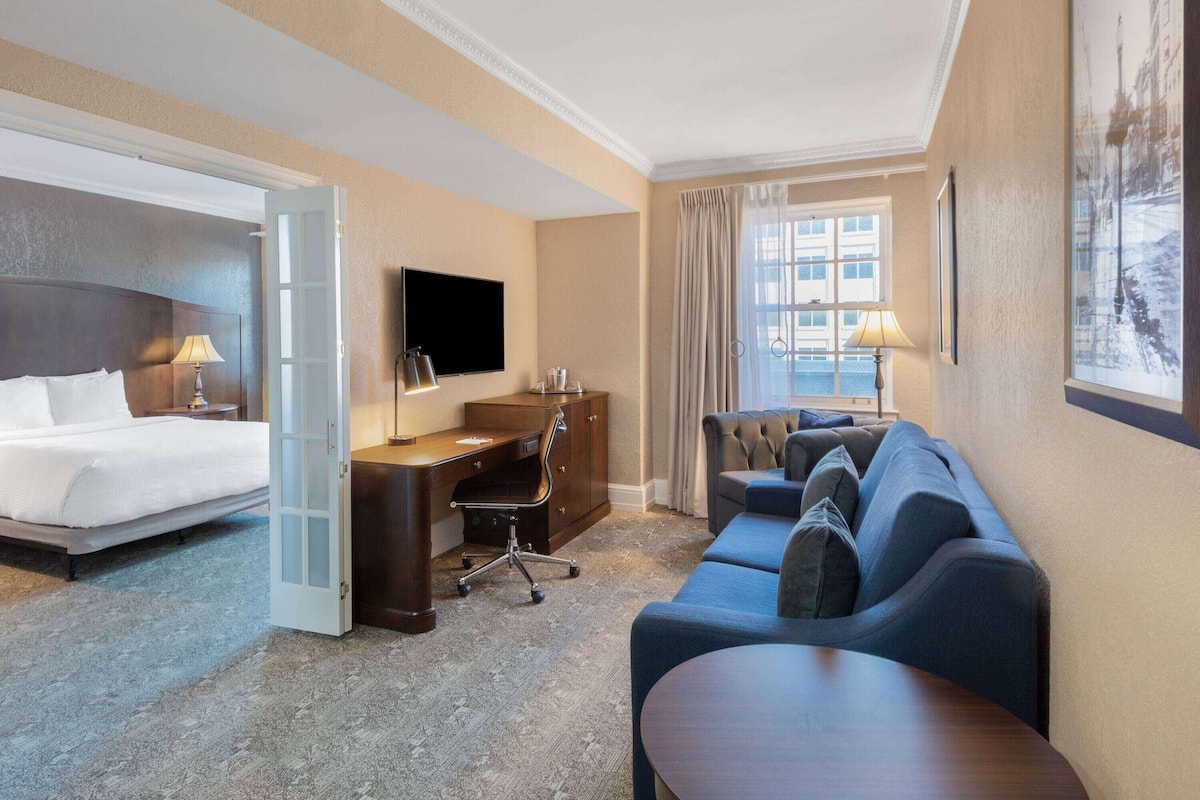 A hotel room with a bed, a desk, a sofa, and a TV.