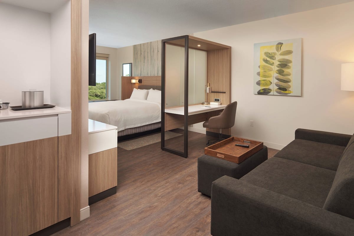 Ein modernes Hotelzimmer mit Bett, Schreibtisch und Sitzecke.