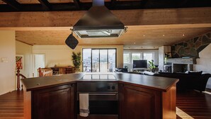 A spacious kitchen with a large island, built-in oven, and a stone fireplace. - Penthouse Apartment (Bergen)