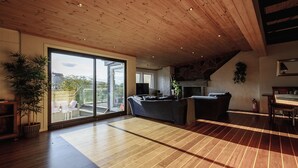 A spacious living area with a wooden ceiling, a large sliding glass door leading to a balcony, and a fireplace. - Penthouse Apartment (Bergen)