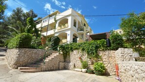 Un edificio a più piani con facciata in pietra, una scala che conduce all'ingresso e piante in vaso nella zona di accoglienza.