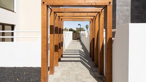A wooden pergola structure leading to a building entrance. - Apartamento con Terraza y piscina Pueblo Majorero (Caleta de Fuste - Antigua)