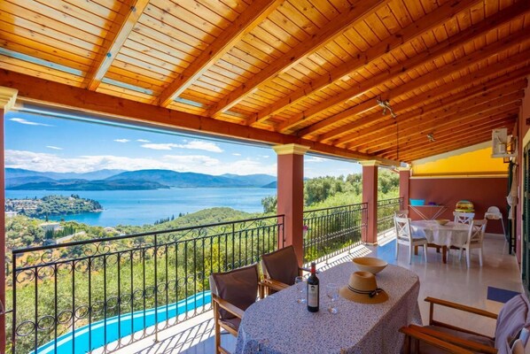 Un balcón con una mesa lista para comer, con vistas a un lago y montañas.