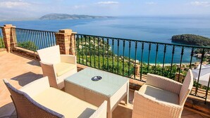 A terrace with wicker furniture and a view of the sea.