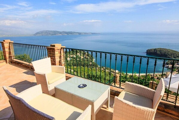 Eine Terrasse mit Korbmöbeln und Meerblick.