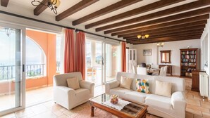 A spacious living room with a balcony, a dining area, and a library.