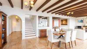 A spacious living area with a staircase, a dining table, and a kitchen area.
