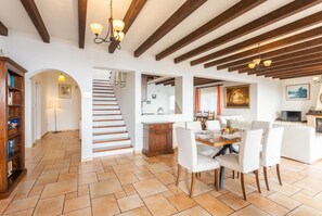 Un grand espace de vie comprenant un escalier, une table à manger et un coin cuisine.
