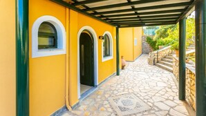 A covered walkway with yellow walls and stone flooring, leading to a stone staircase.