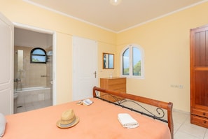 Une chambre avec un lit, une armoire en bois, une salle de bain avec douche et une fenêtre.