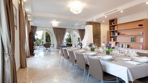 A dining area with a long table set for a meal, surrounded by chairs, with a bookshelf and a decorative vase on the table.