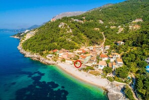 Eine Luftaufnahme einer Küstenstadt mit Gebäuden an einem Hügel mit Blick auf ein klares, blaues Meer.