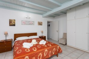 Um quarto com uma cama, mesas de cabeceira, um guarda-roupa e obras de arte nas paredes.