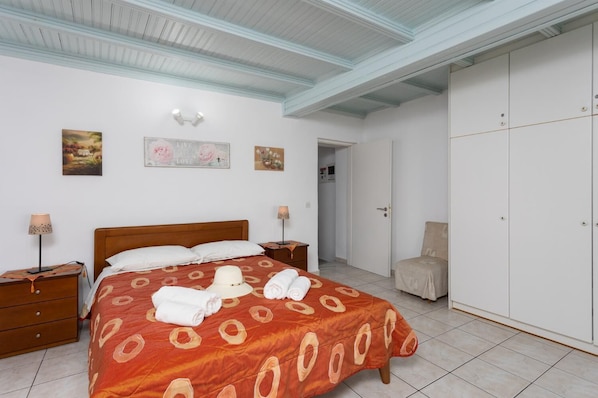 Un dormitorio con cama, mesitas de noche, un armario y obras de arte en las paredes.