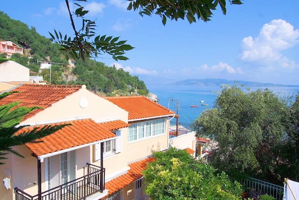 Un bâtiment situé sur la côte, doté d’un toit recouvert de tuiles rouges, d’un balcon et offrant une vue sur la mer.