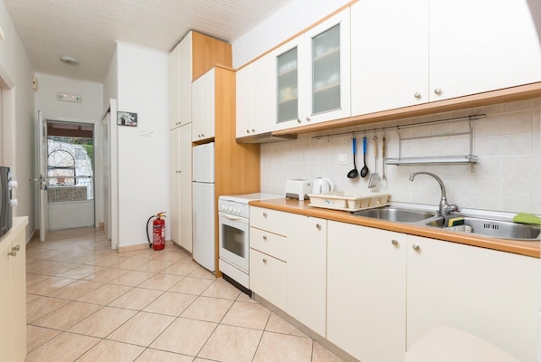 Une cuisine avec des armoires blanches, un plan de travail en bois, un évier et une cuisinière.