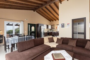 Un salon confortable avec un canapé d’angle, un coin repas avec une table et des chaises, une cuisine équipée d’appareils modernes et un balcon avec vue.