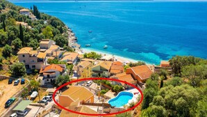 Un pueblo costero con una piscina rodeada de casas y una vista despejada del mar.