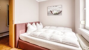 A bedroom with a bed, a wooden door, a radiator, and a wall-mounted picture. - Vacation apartment Waldesruh (Thale)