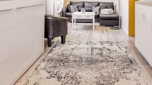 A modern living room with a flat-screen TV, a sofa, a coffee table, and a patterned rug. - Vacation apartment Waldesruh (Thale)