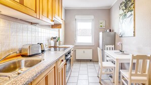 A kitchen with wooden cabinets, a granite countertop, a sink, a toaster, and a dining table with chairs. - Vacation apartment Waldesruh (Thale)