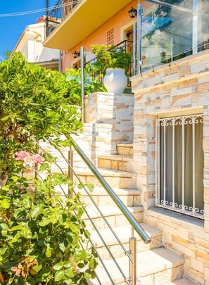 Stunning Mediterranean-style building with a grand staircase, lush greenery, and a decorative urn.