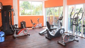 Et fitnesscenter med diverse træningsmaskiner, store vinduer og orange vægge.