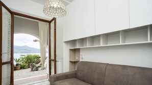 Een woonkamer met een bank, een hanglamp, uitzicht op de omgeving en een deur naar een balkon.