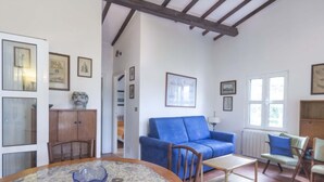 A room with a blue sofa, wooden chairs, a table, and various framed pictures on the walls. - Small Villa on the sea with garden for the perfect holiday (Portoferraio)