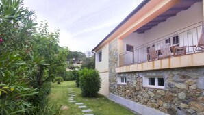 A two-story house with a stone facade, a balcony with outdoor furniture, and a garden with a stone pathway. - Small Villa on the sea with garden for the perfect holiday (Portoferraio)