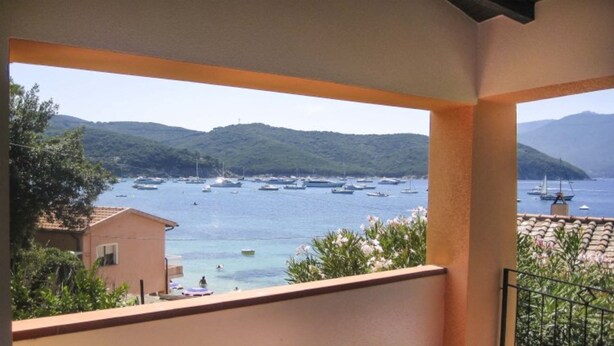 A balcony with a view of boats on the water and hills in the background. - Small Villa on the sea with garden for the perfect holiday (Portoferraio)