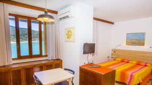 Une chambre avec un lit, un bureau, une chaise, une table et une vue sur la mer.