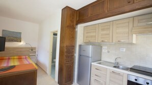 Une cuisine compacte avec des meubles en bois, un réfrigérateur en acier inoxydable et un four encastré.
