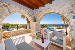 Un espacio al aire libre con paredes de piedra, piscina y vista al mar.