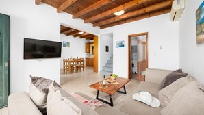 Un salon comprenant un canapé, une table basse, un téléviseur et un escalier menant à une salle de bain.