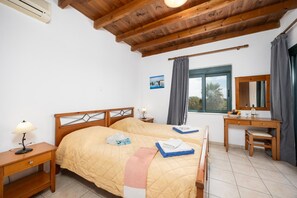Ein Schlafzimmer mit einem hölzernen Bett, Nachttischen, einem Schreibtisch und einem Fenster mit Vorhängen.