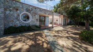 Una casa moderna con fachada de piedra, un ventanal circular y un espacio exterior cubierto.