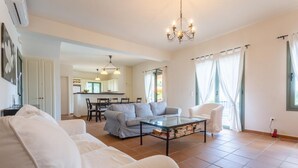 Un salon spacieux avec un canapé, une table basse et un coin repas à l’arrière-plan.