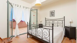 Une chambre à coucher comprenant un lit, une table de chevet, une chaise, une armoire et un balcon avec vue.