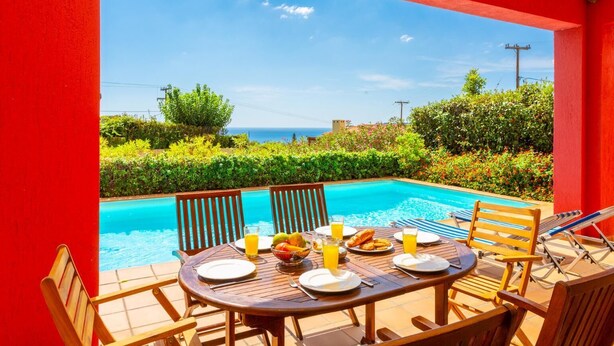Un espace repas aménagé au bord de la piscine, avec une table dressée pour deux personnes, offrant une vue sur la piscine et un panorama magnifique sur la mer.