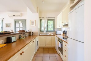 A kitchen with white cabinets, a wooden countertop, a built-in oven, a microwave, and a refrigerator.