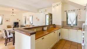 A modern kitchen with a central island, white cabinetry, and a built-in washing machine. - Villa Katerina - Three Bedroom Villa, Sleeps 6 (Afrato)